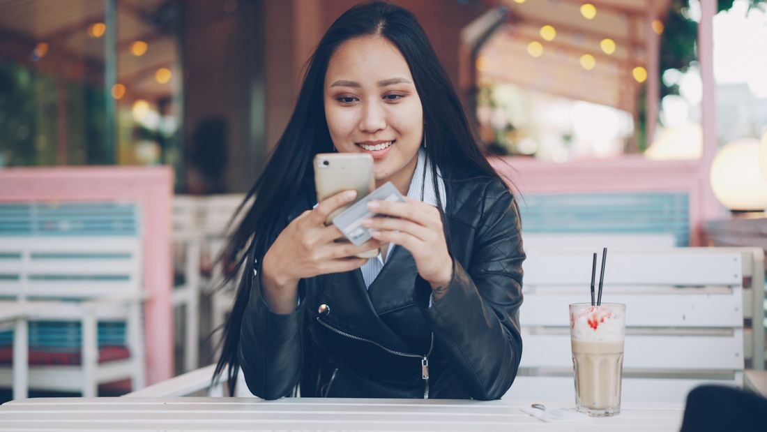 Asian woman shopping on her phone with a card